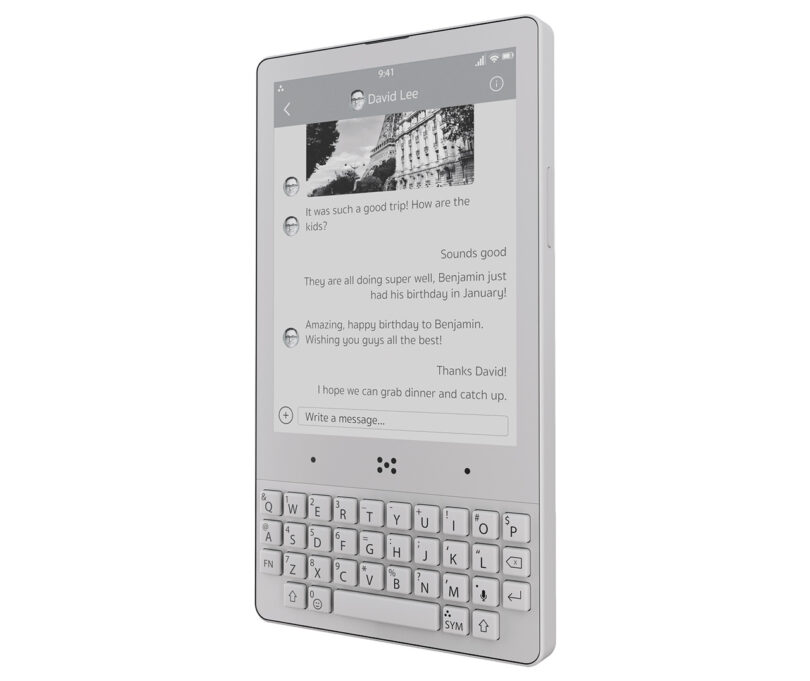 A slim e-ink screen device with a tactile keyboard displays a messaging conversation screen. The e-ink screen shows messages that include greetings and mentions of a trip and a birthday.