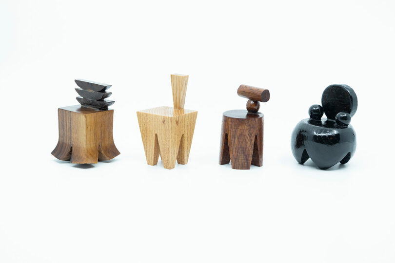 Four small, wooden objects of various shapes and colors are arranged in a row against a white background.
