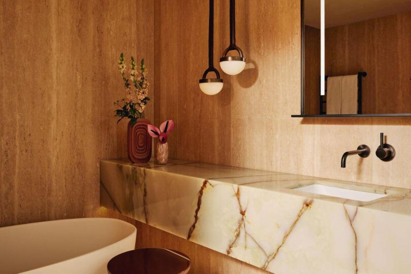 The Emory hotel bathroom features a marble countertop, wooden walls, hanging pendant lights, and a bathtub partly visible on the left.