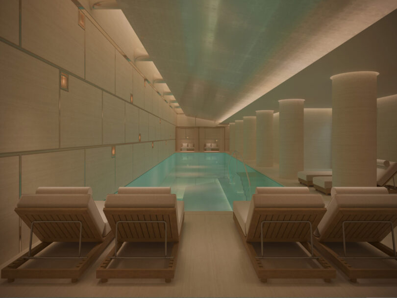 An indoor pool at The Emory hotel with teal water under a low ceiling, flanked by wooden lounge chairs and cylindrical columns in a dimly lit, serene setting.