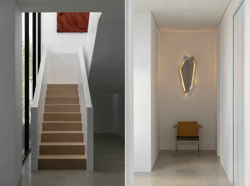 A modern interior with a wooden staircase and abstract wall art on the left, and a hallway with a geometric wall light and a chair against a white wall on the right.