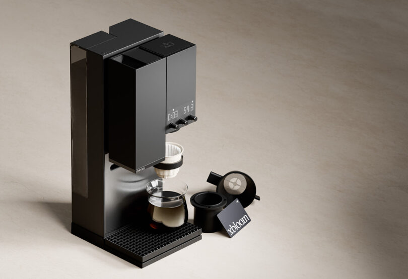 xBloom Studio in midnight black finish from overhead angled view, showing machine with carafe, filters, and coffee pod