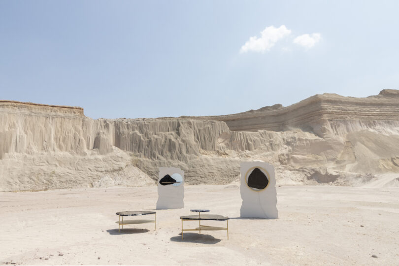two coffee tables and two white walls with mirrors hung in the middle of a desert-like background