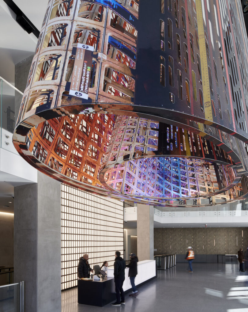 people in a lobby featuring a colorful public art installation made of metal panels