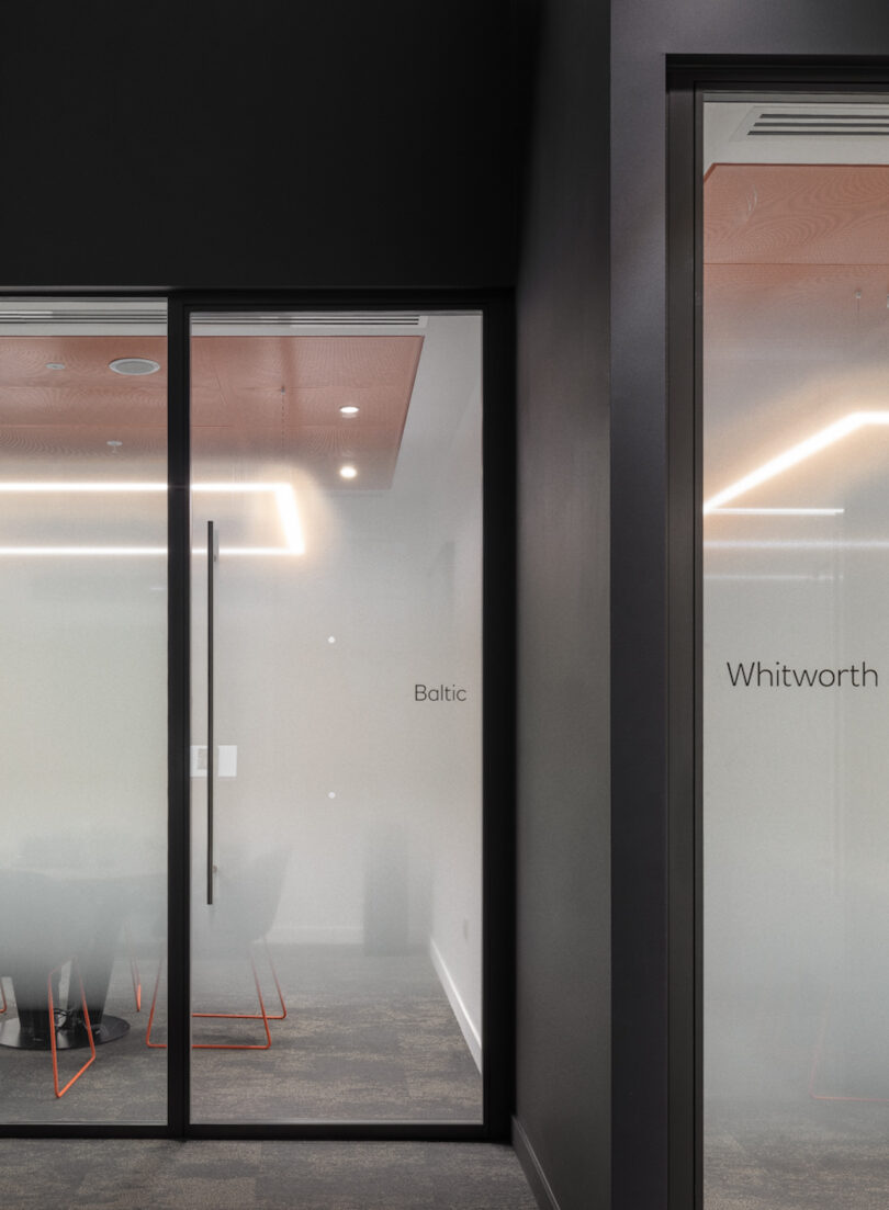 Two glass office doors labeled "Baltic" and "Whitworth" with modern interior lighting and minimal visible furniture
