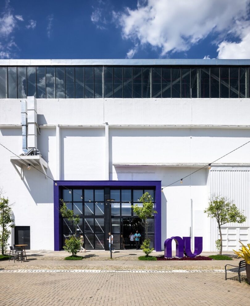 Facade of a modern white building with a distinctive purple entrance and large glass doors, under a clear blue sky
