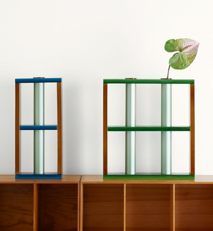 two vases, one with a plant stem inside, on a brown shelf