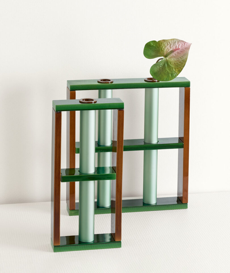 two metal vases supported by ceramic framework, one vase has a plant in it