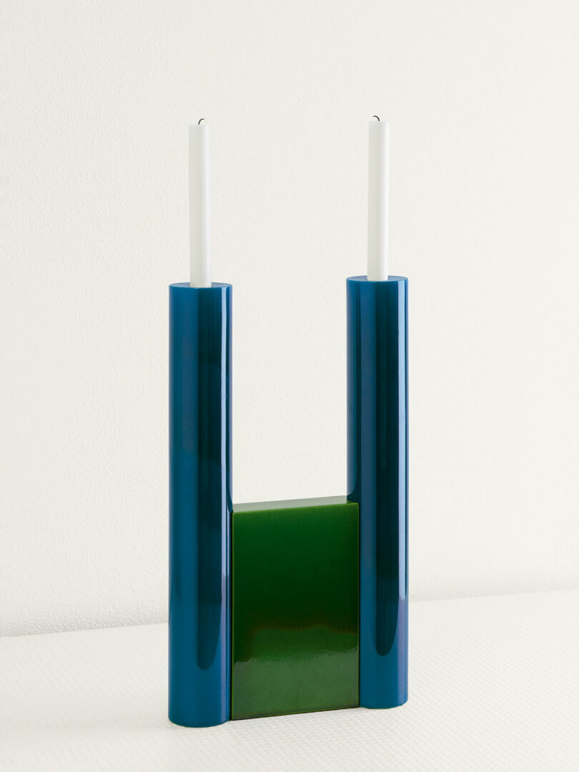 blue and green candelabra holding 2 white tapered candles