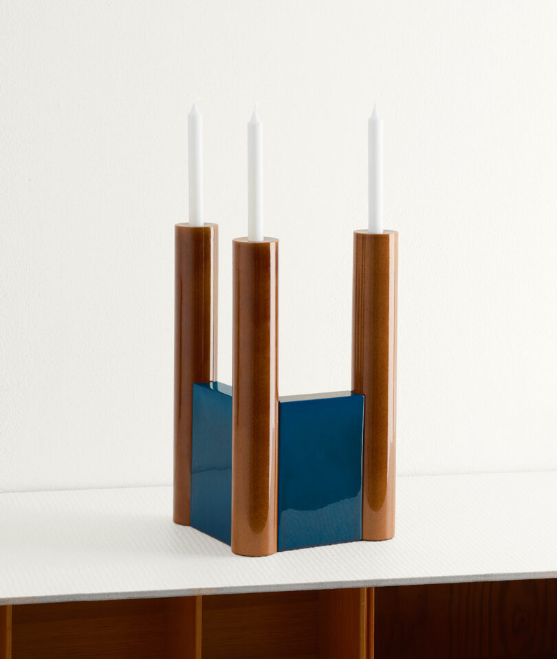 blue and brown candelabra holding 3 white tapered candles