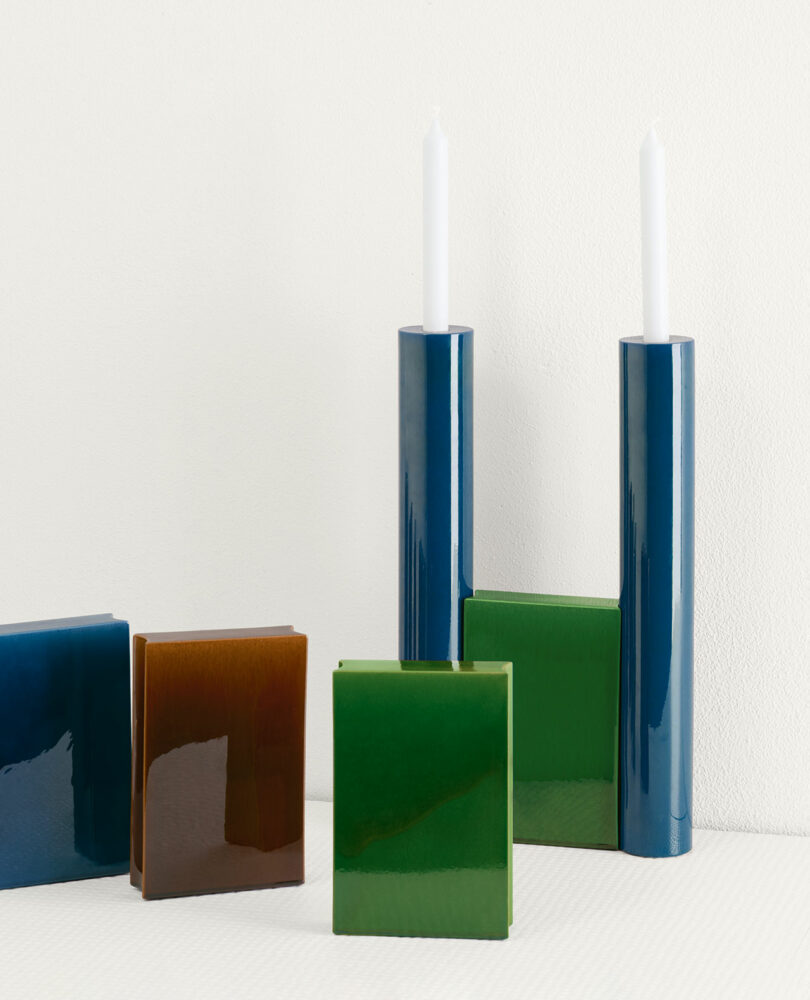 blue and green candelabra holding 2 white tapered candles next to connecting elements