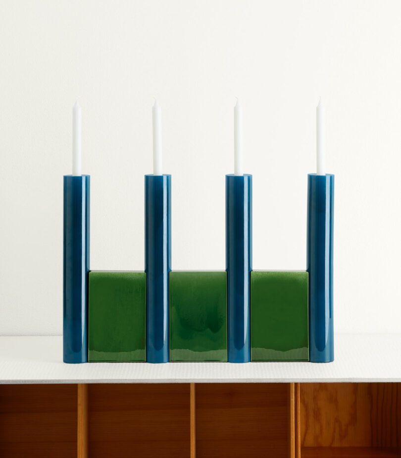 blue and green candelabra holding four white tapered candles