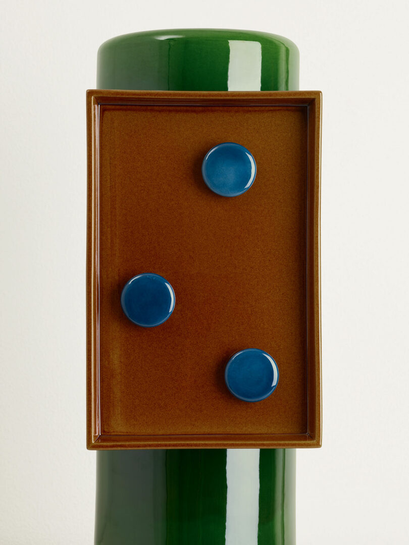 green vase with brown and blue panel with three circles attached