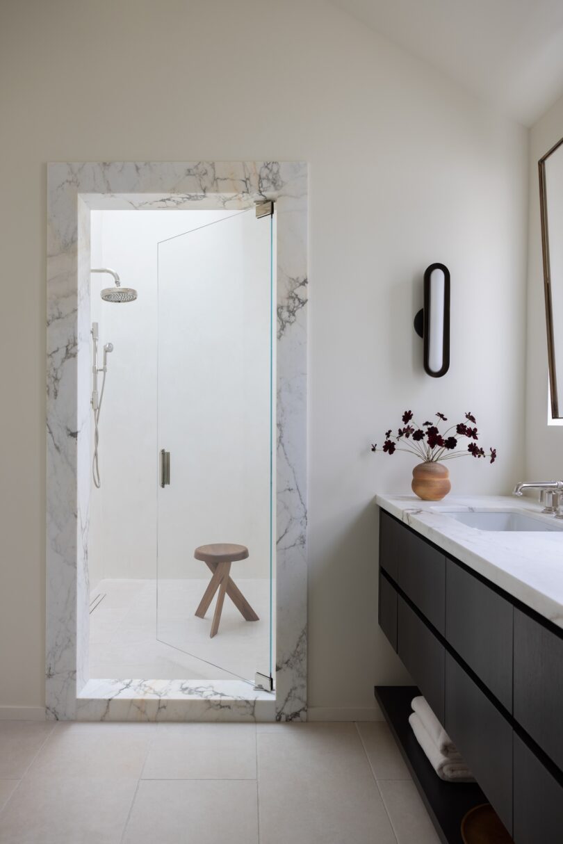 A modern bathroom featuring a shower with a glass door and marble trim.