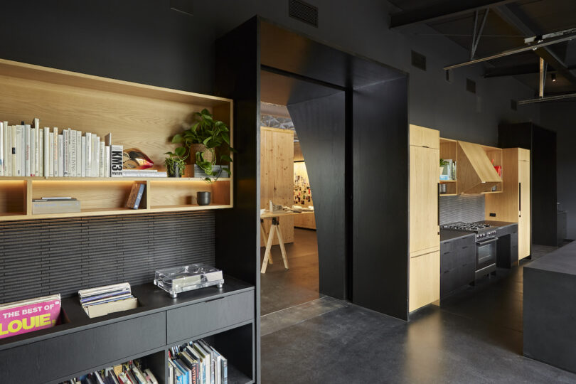 office area with black cabinets, wooden bookshelves, a countertop with books, and plants in a well-lit space