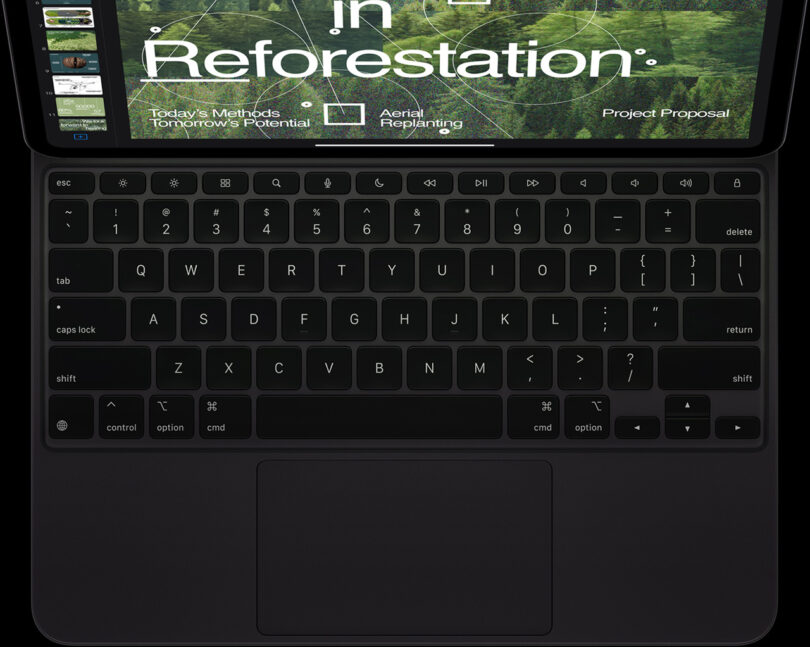 A close-up view of the Apple iPad Pro Magic Keyboard and touchpad, displaying a presentation about reforestation on the screen.