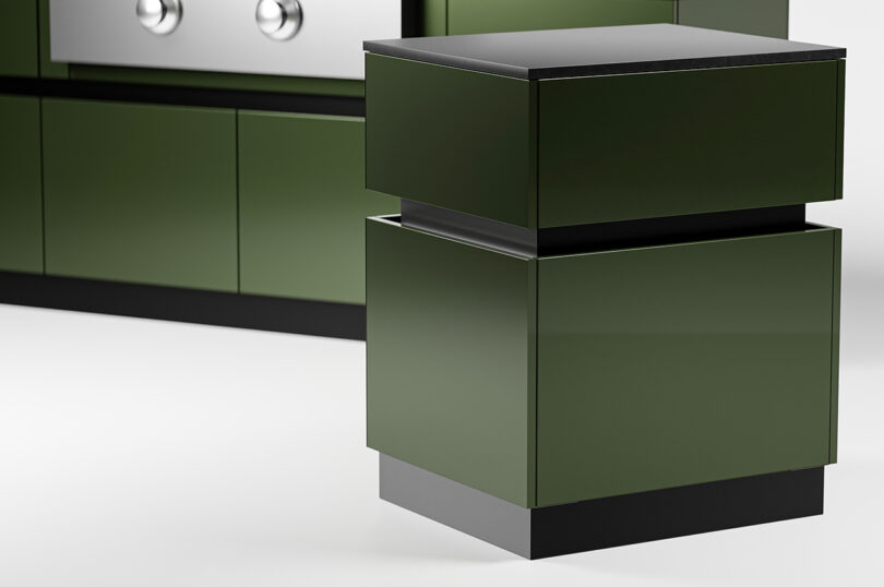 A modular olive-green outdoor kitchen drawer unit stands on a white floor, positioned in front of a matching set of lower kitchen cabinets.