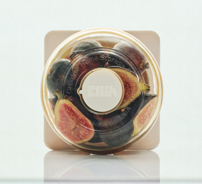 A transparent round container filled with fresh figs, viewed from the top.