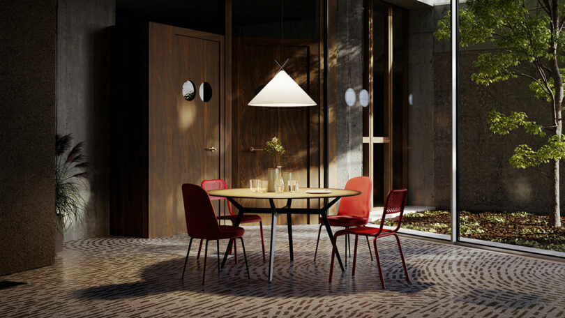 A modern dining area with a round table, four red chairs, a pendant light, and a large window revealing greenery outside. The space has wooden doors and a patterned floor.