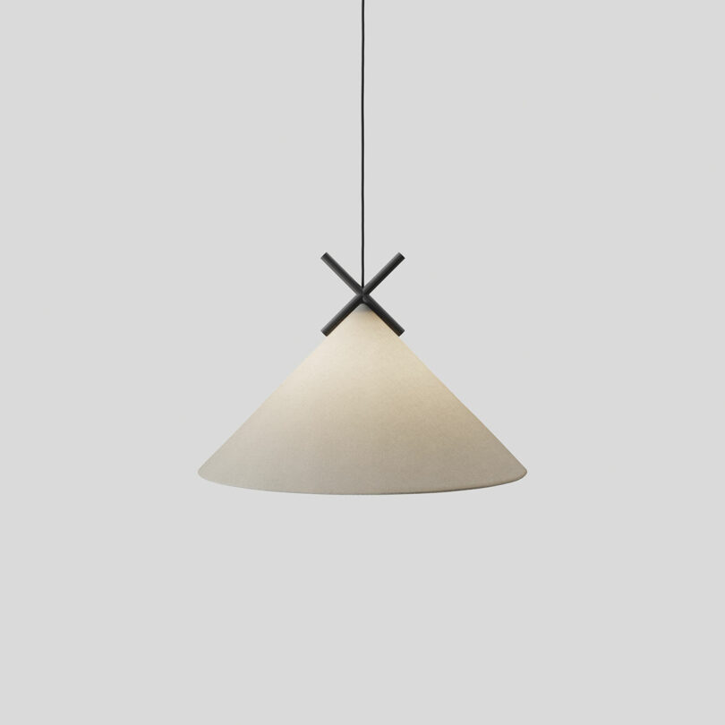 A conical pendant light with a white shade and black cross-frame, suspended from the ceiling by a black cord against a plain white background.