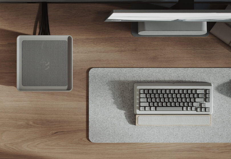 Overhead of a desk with Fractal Design's light gray textile wrapped Mood, a vertical gaming PC case set across a desk alongside a keyboard, mouse and monitor.