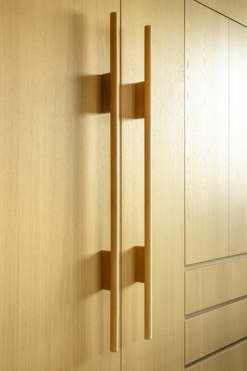 Close-up of a wooden cabinet with long, vertical handles and horizontal grooves.