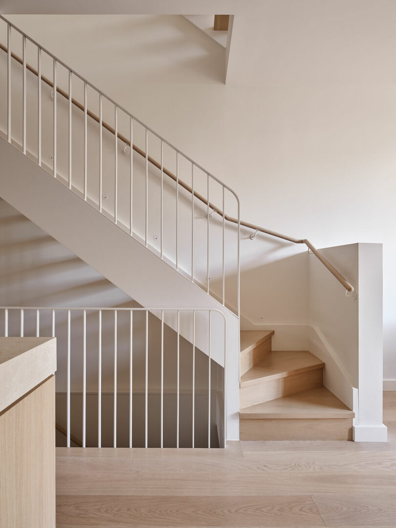 A minimalist indoor staircase with light wood steps and white railings, featuring clean lines and modern design elements.