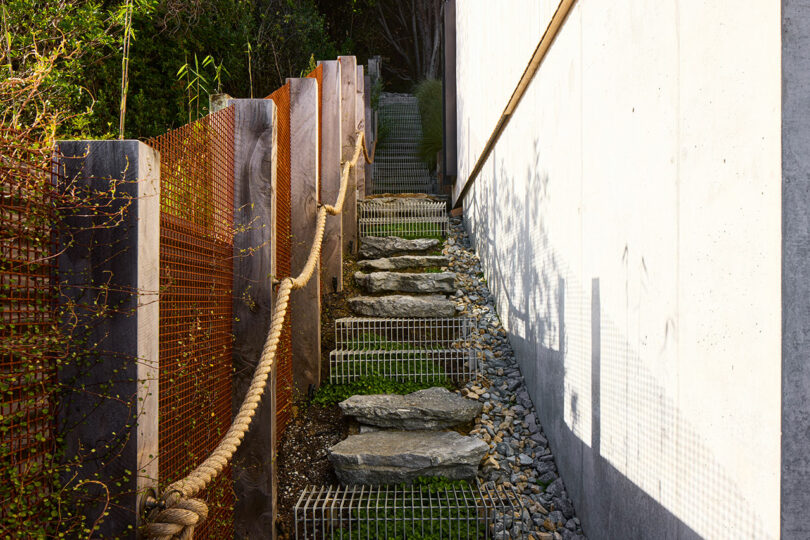 Exterior shot of handmade outdoor staircase next to a house that's made of steel and stones.