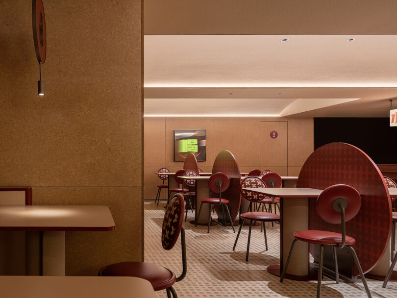 A chic indoor café within the NI HAO Hotel, featuring modern round tables, red chairs, and soft lighting. Walls and furniture exhibit earth tones, creating a warm, inviting atmosphere.