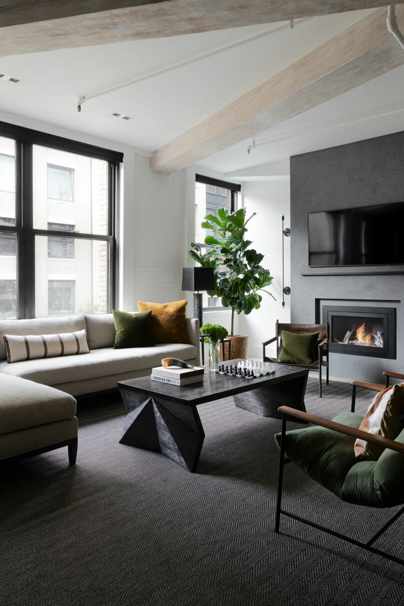 A modern living room with large windows, a sectional sofa, armchairs, a black coffee table, a fireplace, a TV on the wall, green accents, and a large potted plant.