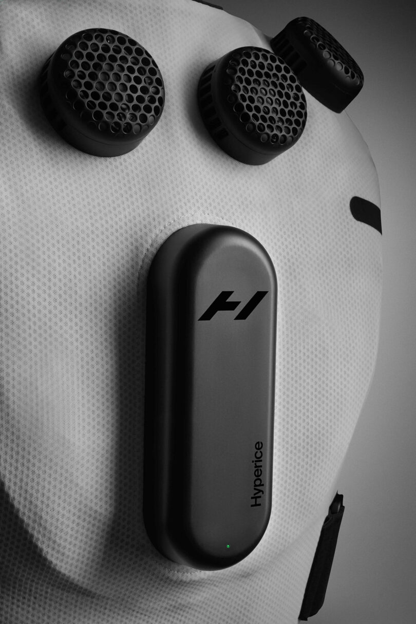 Close-up of a white Hyperice recovery vest featuring cutting-edge recovery technology, with three circular black vents and a sleek black control panel.