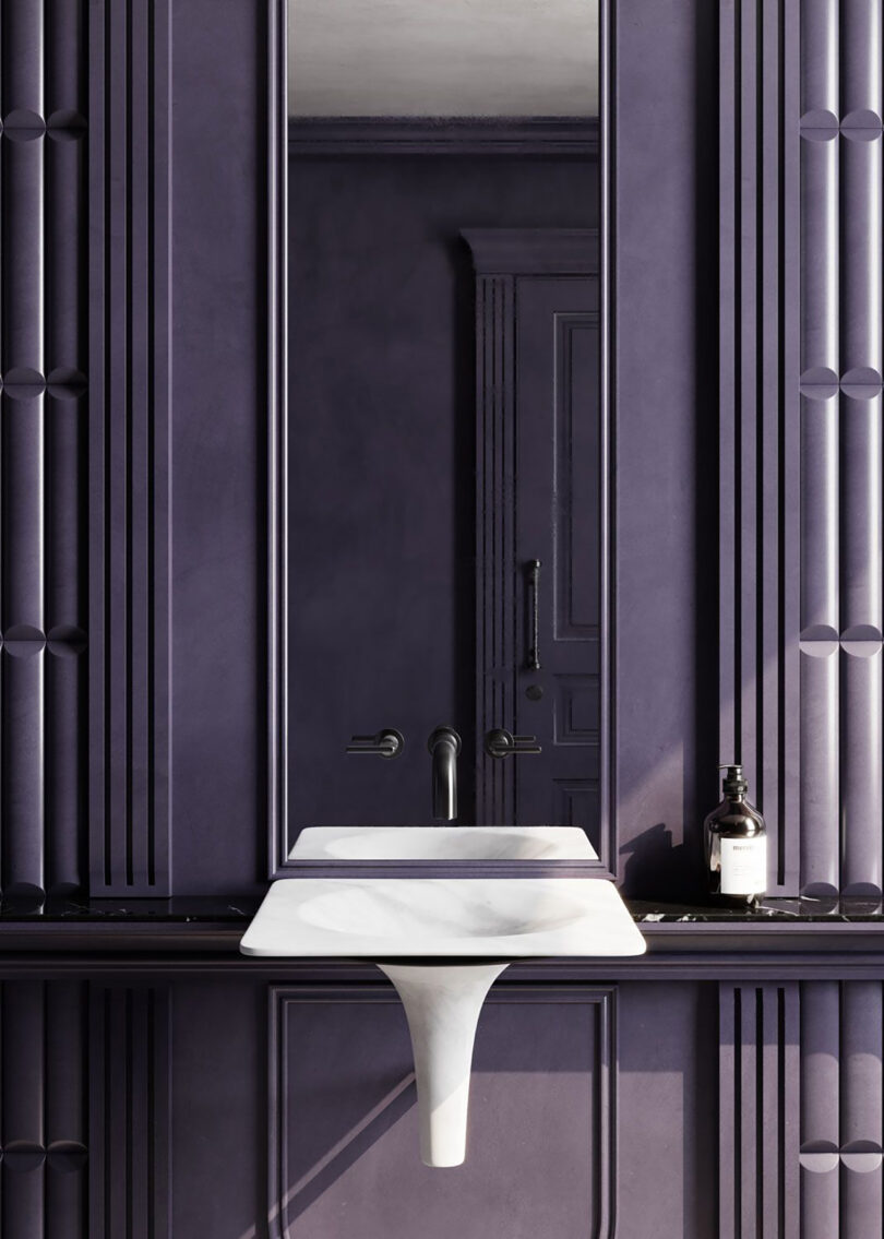 A minimalist bathroom with dark purple walls, a large mirror, a sleek INFINITO white sink, and a black faucet. A bottle is placed on the counter beside the sink.