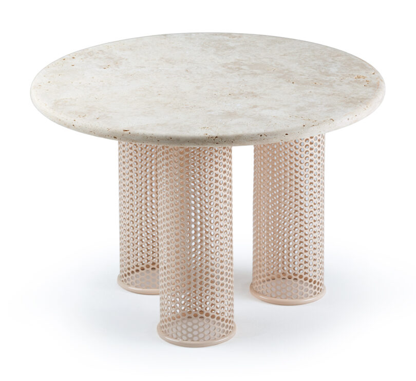 A round table with a terrazzo top and three cylindrical mesh legs.
