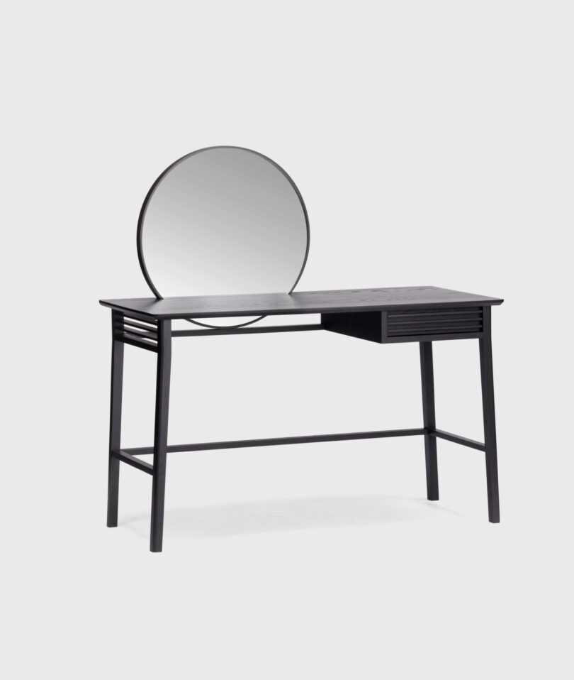 A contemporary table with one drawer on the right side and mirror attached to the desk surface.