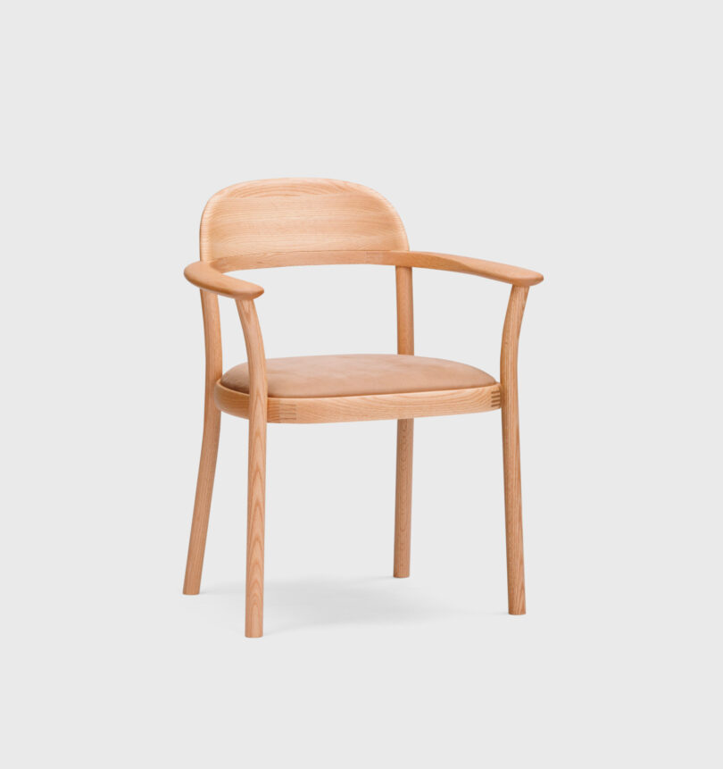 A light-colored wooden chair with a curved backrest and armrests, and a padded seat cushion