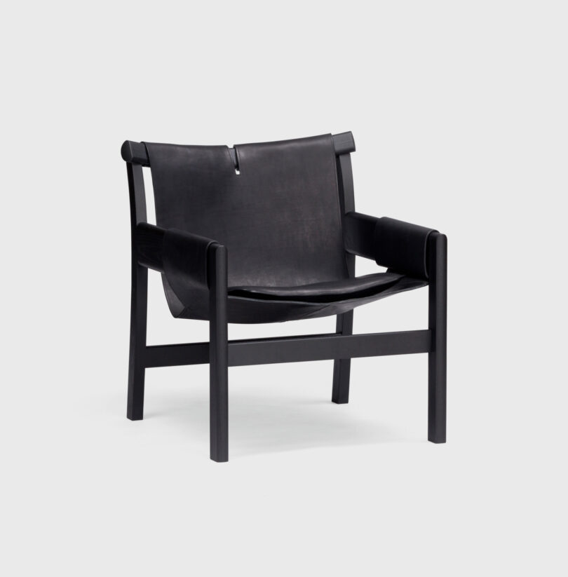 A black, modern-style lounge chair with a leather seat and backrest on a minimalist wooden frame with four legs