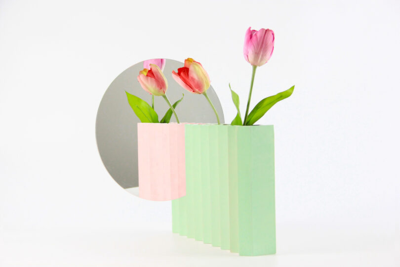 a green and pink zigzag vase with a mirror attached