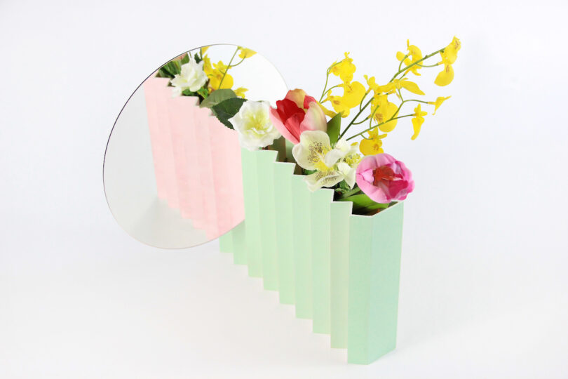 a green and pink zigzag vase with a mirror attached