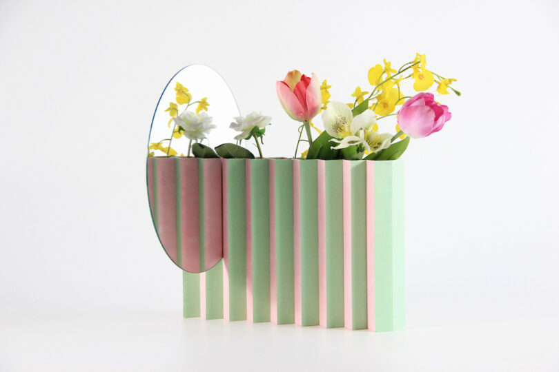 a green and pink zigzag vase with a mirror attached