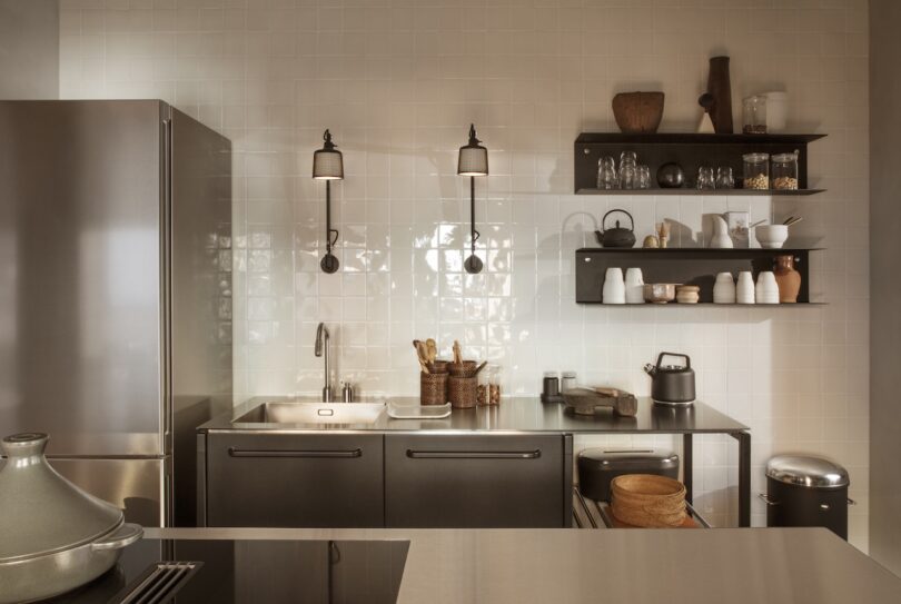 A stylish Vipp V1 kitchen with a clean design, black cabinets, and open shelves holding dishes and cookware