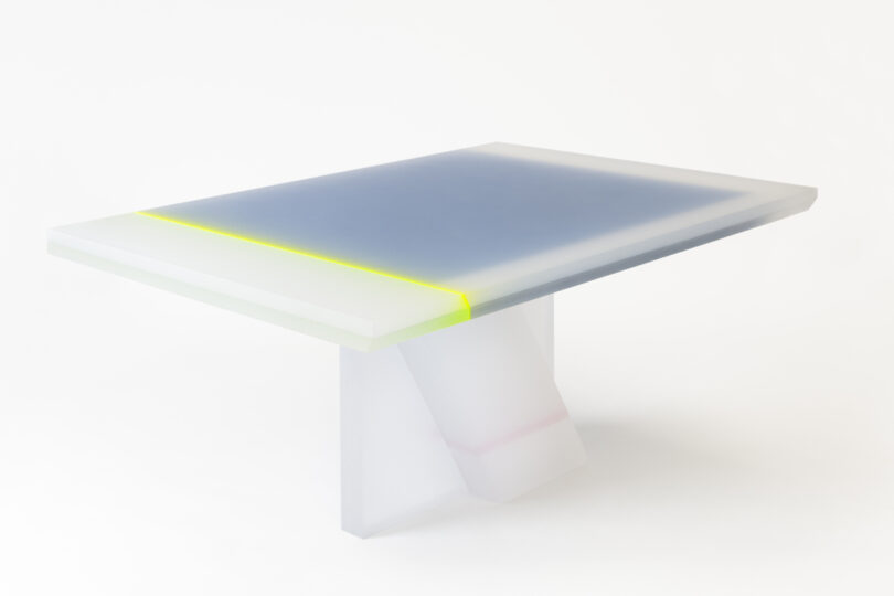 A modern rectangular table with a thick, semi-transparent white base and a smooth surface. The tabletop features a subtle gradient with hints of green and gray.