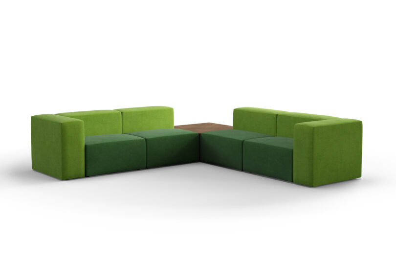 Two L-shaped green sofas with a small wooden table in between them, arranged to form a U-shape
