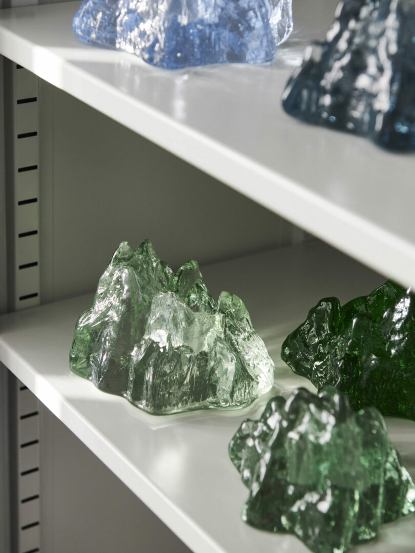 Shelves displaying glass votiveholders in various shades of green and blue.