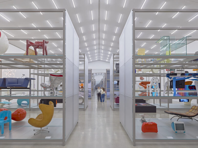 A modern, well-lit gallery features futuristic designs displayed on shelves and pedestals.