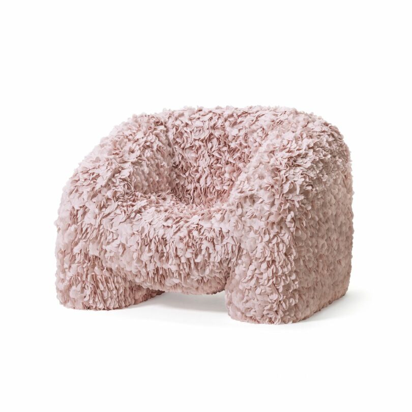 A soft and fluffy pink armchair with a textured, petal-like fabric covering