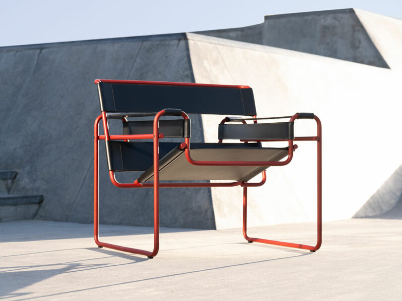 Modern chair with a red metal frame and black slats, set outdoors against a concrete background.