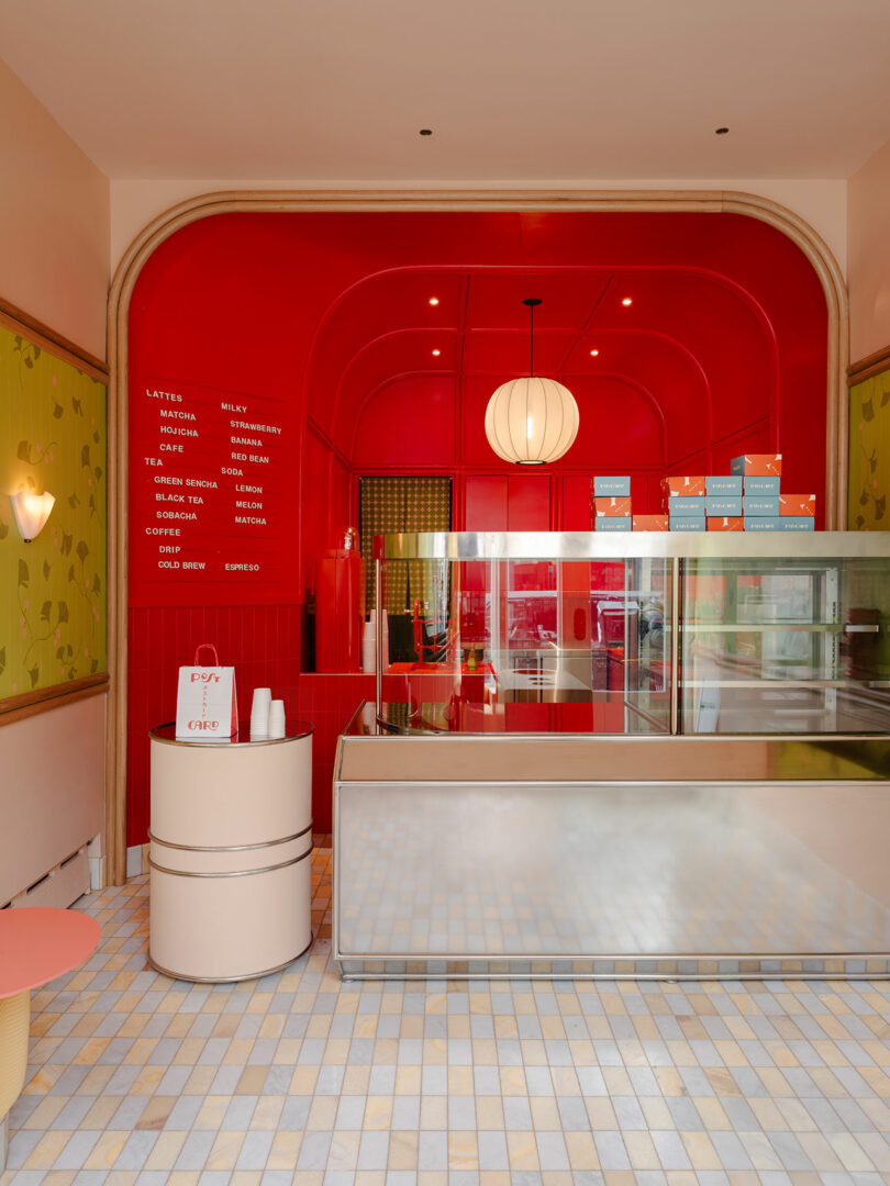 A brightly lit café with a red interior, featuring a modern counter, colorful tiles on the floor, and various coffee-related items displayed.