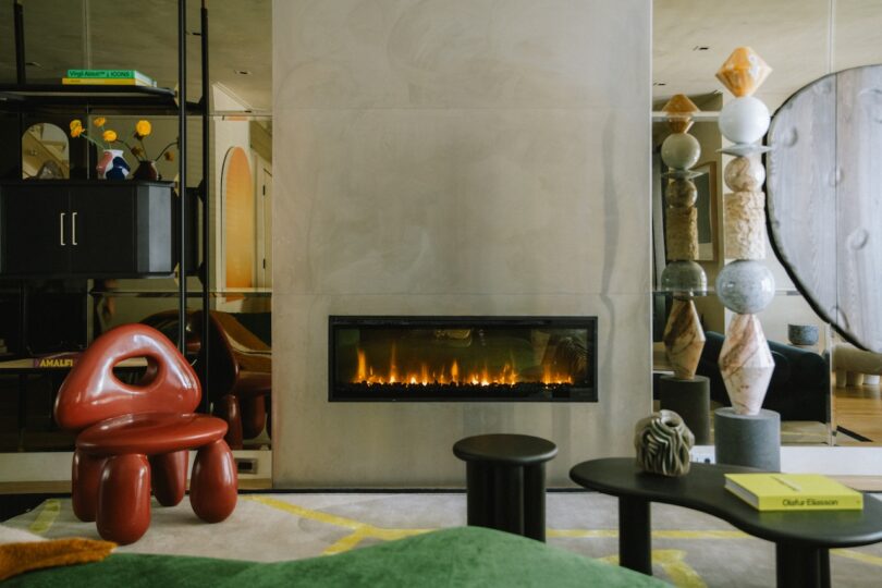 A modern living room with a fireplace, a mirrored wall, and eclectic furniture