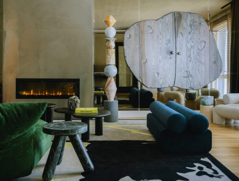 A living room with a fireplace, abstract furniture, and a mirrored wall