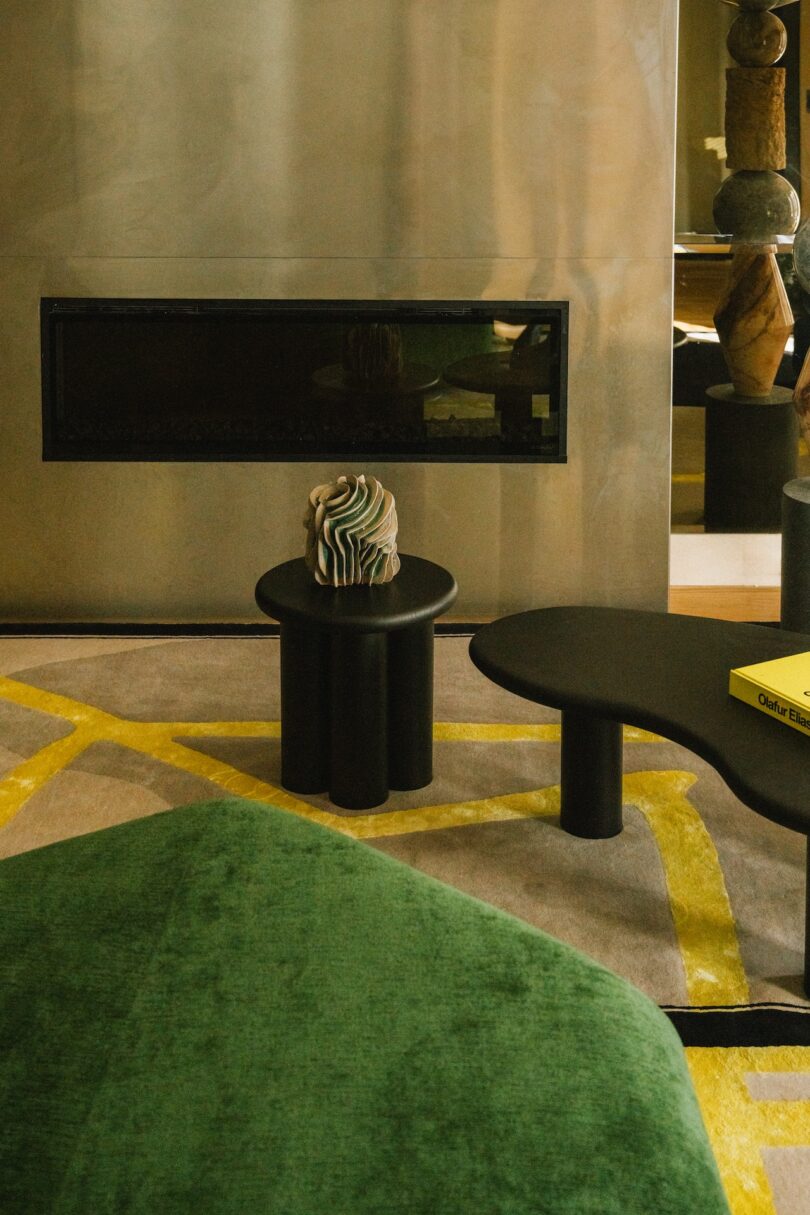 A modern fireplace with a small artistic sculpture on a black side table in front